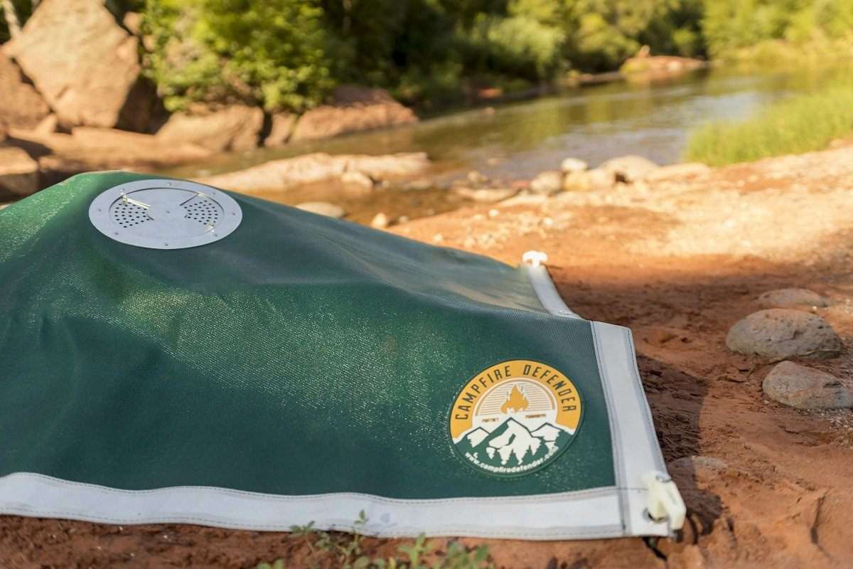 Campfire Defender cover with carrying bag, stakes, gloves, and flashlight for safely maintaining campfire coals